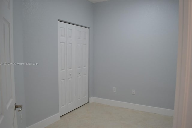 unfurnished bedroom with light carpet and a closet