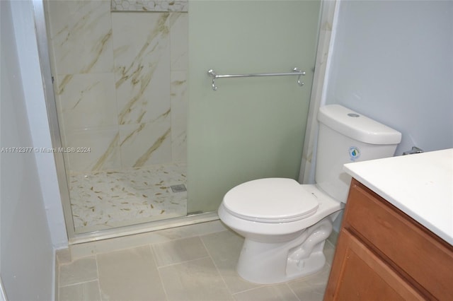 bathroom featuring tile patterned flooring, toilet, vanity, and tiled shower