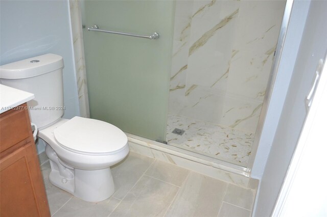 bathroom featuring tiled shower, vanity, tile patterned flooring, and toilet