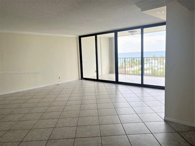 tiled spare room with a textured ceiling, a water view, and floor to ceiling windows