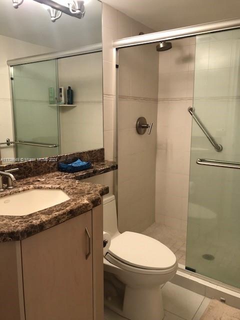 bathroom featuring an enclosed shower, vanity, toilet, and tile patterned flooring