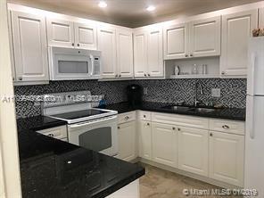 kitchen featuring white appliances, backsplash, white cabinetry, and sink