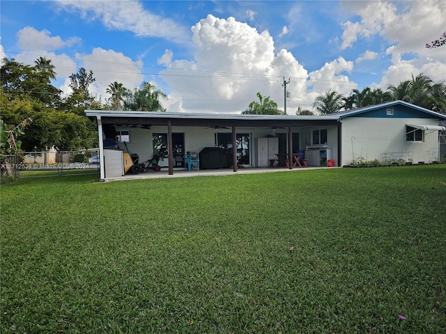 rear view of property with ceiling fan, a yard, and a patio