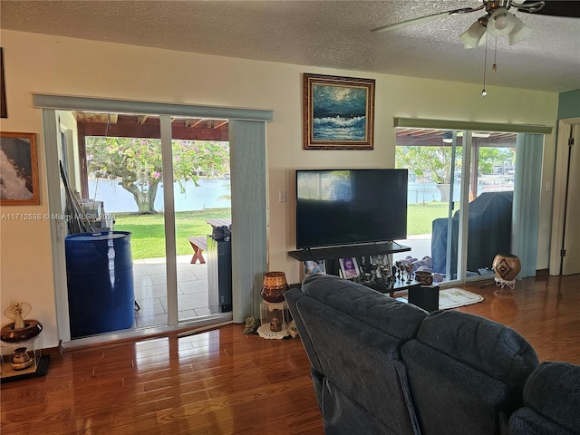 living room with hardwood / wood-style flooring, ceiling fan, and a textured ceiling