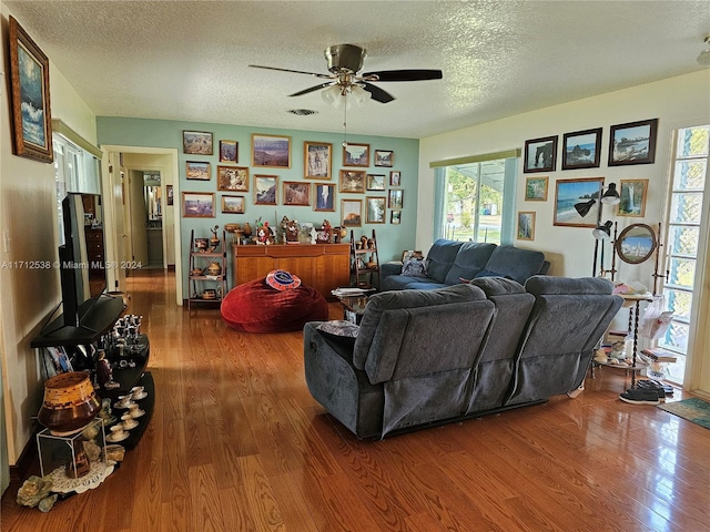 living room featuring a textured ceiling, hardwood / wood-style flooring, and ceiling fan