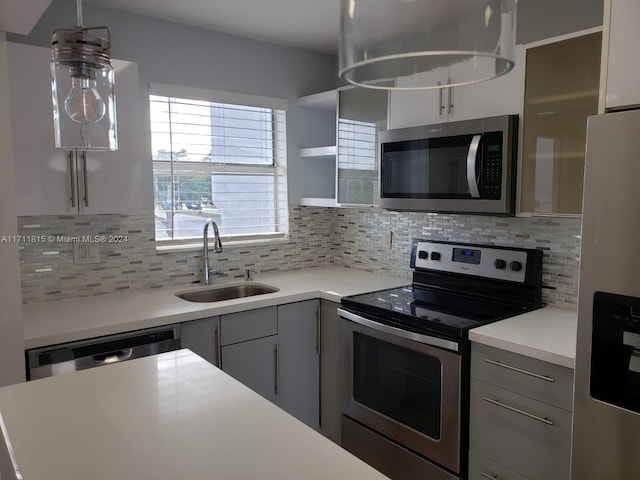 kitchen with hanging light fixtures, gray cabinetry, sink, and stainless steel appliances