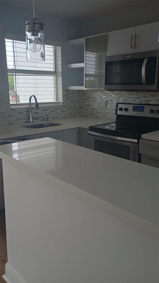 kitchen with decorative light fixtures, sink, decorative backsplash, and stainless steel appliances