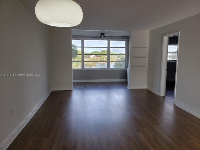 unfurnished room featuring a healthy amount of sunlight, ceiling fan, and dark wood-type flooring