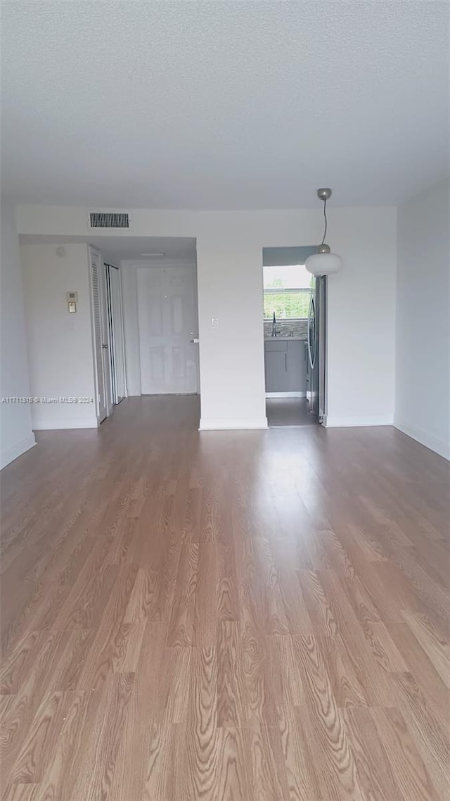 spare room with sink, a textured ceiling, and light wood-type flooring