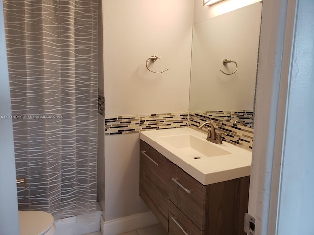 bathroom with decorative backsplash, vanity, and toilet