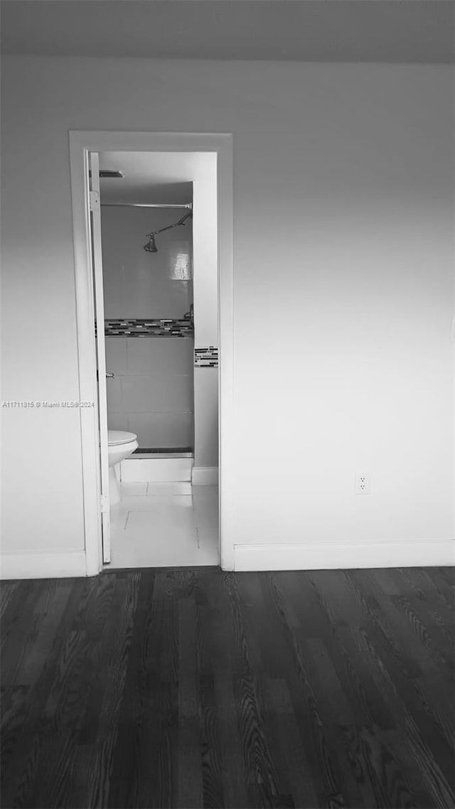 bathroom featuring hardwood / wood-style floors, toilet, and tiled shower