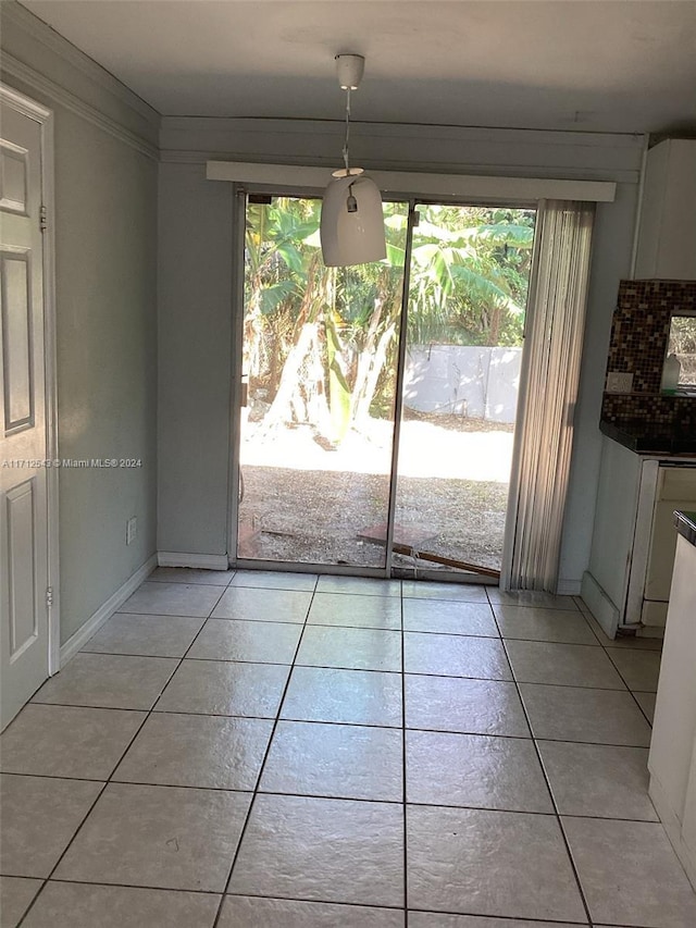 unfurnished dining area featuring plenty of natural light, light tile patterned flooring, and ornamental molding