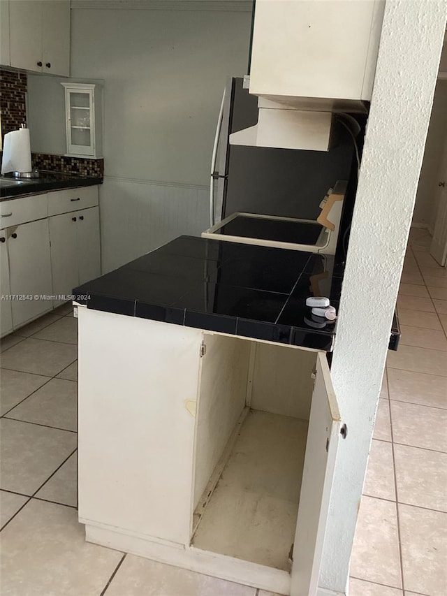 kitchen with white cabinets, light tile patterned floors, and kitchen peninsula