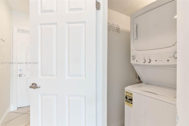 washroom with light tile patterned floors, stacked washing maching and dryer, and a textured ceiling