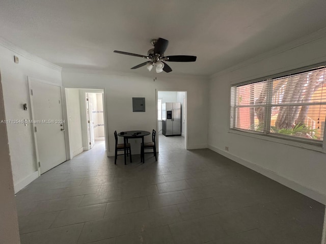 tiled empty room featuring ceiling fan, crown molding, and electric panel