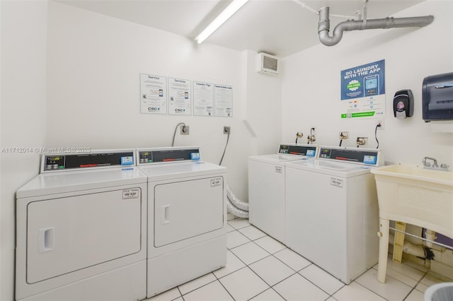 clothes washing area featuring sink, light tile patterned floors, and independent washer and dryer