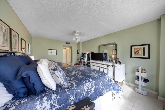 bedroom with light tile patterned floors, visible vents, a ceiling fan, a textured ceiling, and baseboards