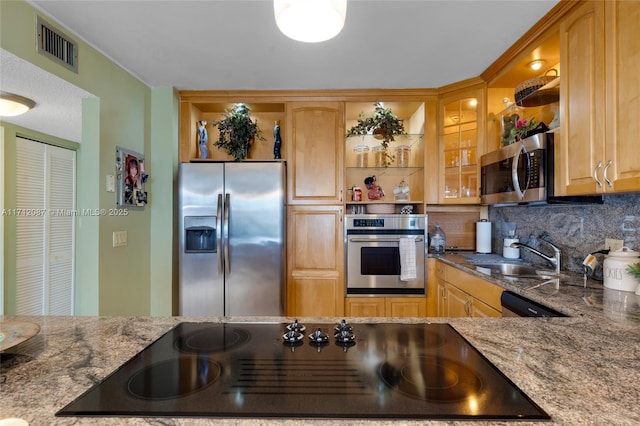 kitchen with stainless steel appliances, tasteful backsplash, visible vents, a sink, and dark stone counters