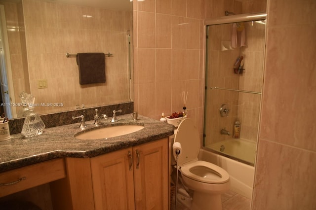 full bathroom with toilet, vanity, tile walls, and combined bath / shower with glass door