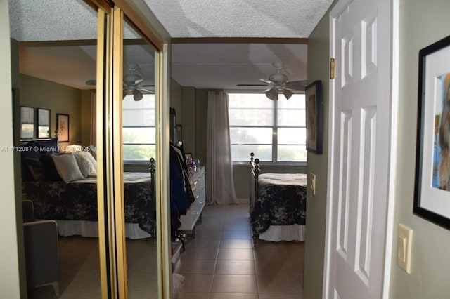 bedroom with tile patterned flooring, ceiling fan, and a textured ceiling