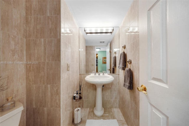 bathroom with tile walls and toilet