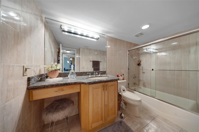 bathroom featuring tile walls, bath / shower combo with glass door, visible vents, toilet, and vanity