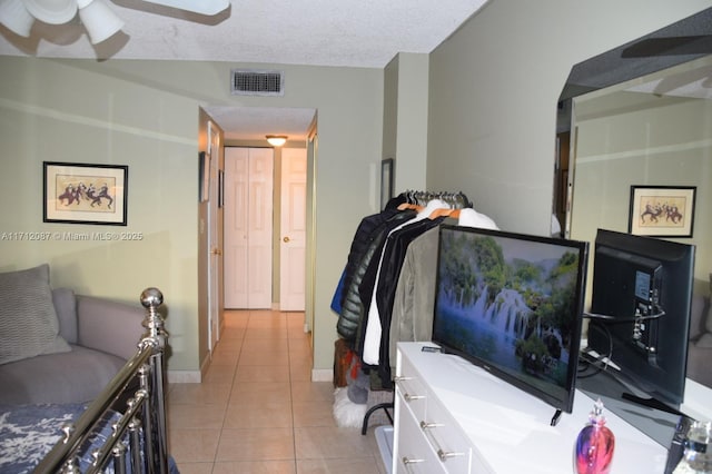 bedroom featuring ceiling fan, a textured ceiling, and light tile patterned floors