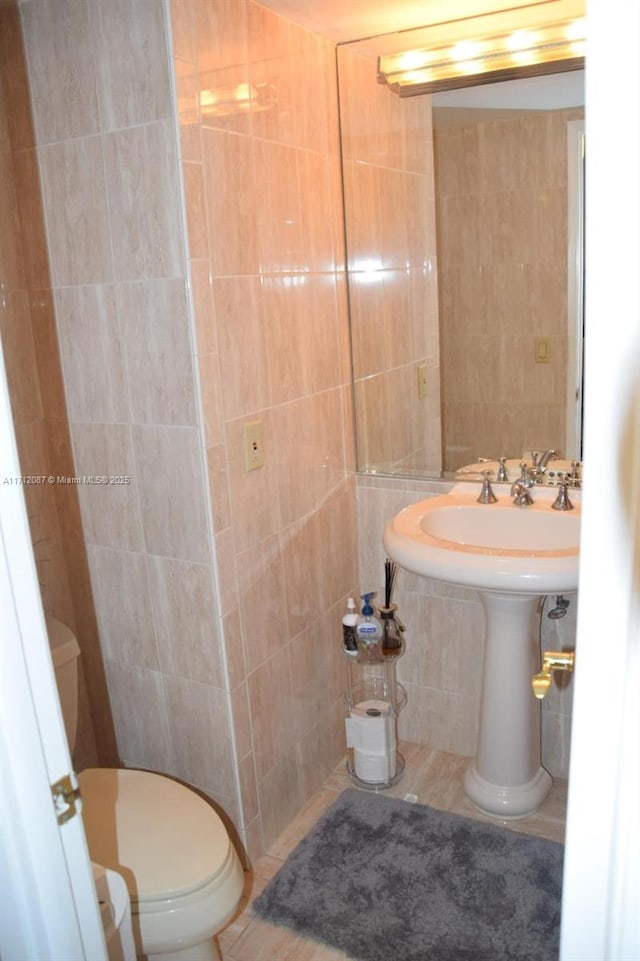 bathroom featuring tile walls and toilet