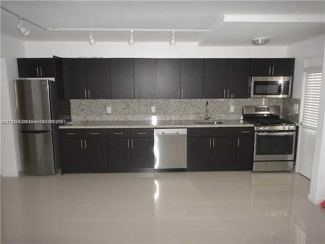 kitchen with backsplash, sink, rail lighting, and appliances with stainless steel finishes