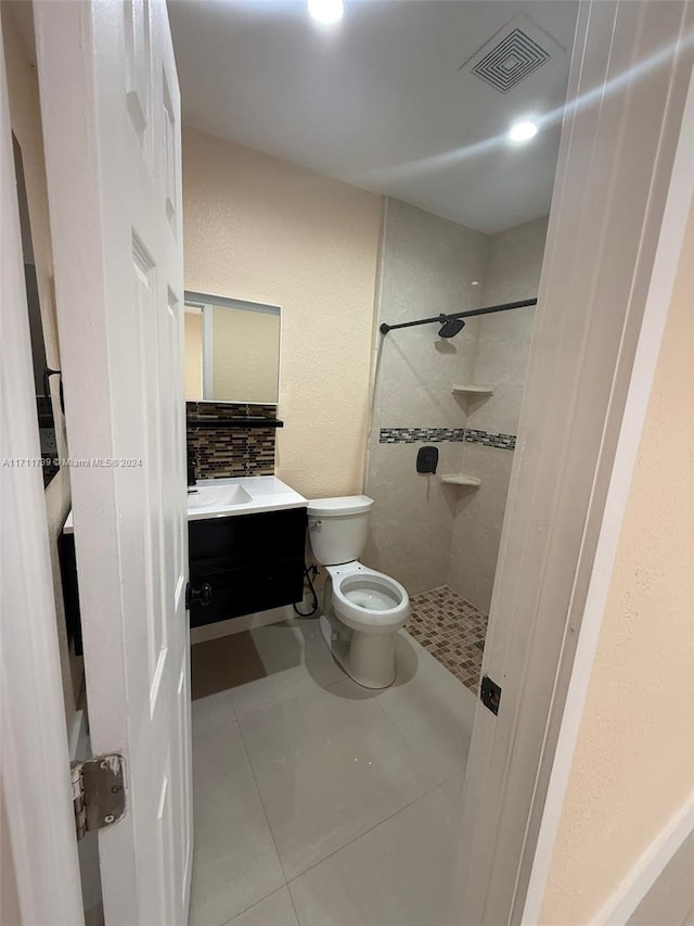 bathroom with tile patterned floors, toilet, a tile shower, and vanity