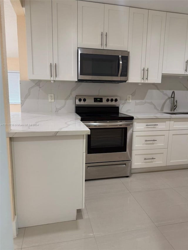 kitchen featuring light stone countertops, light tile patterned floors, stainless steel appliances, and sink