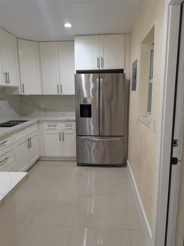 kitchen featuring backsplash, stainless steel fridge, and white cabinets