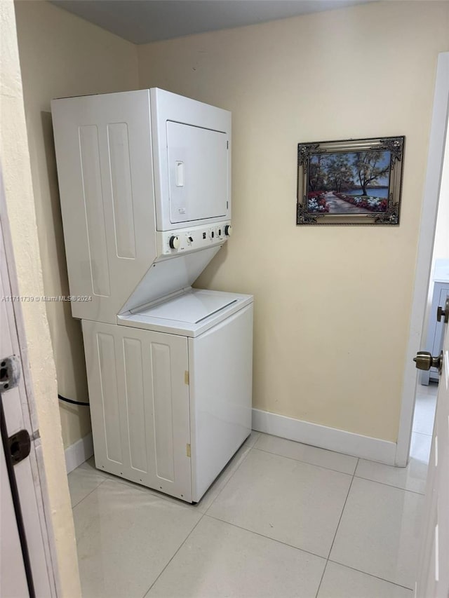 laundry area with light tile patterned floors and stacked washer and clothes dryer