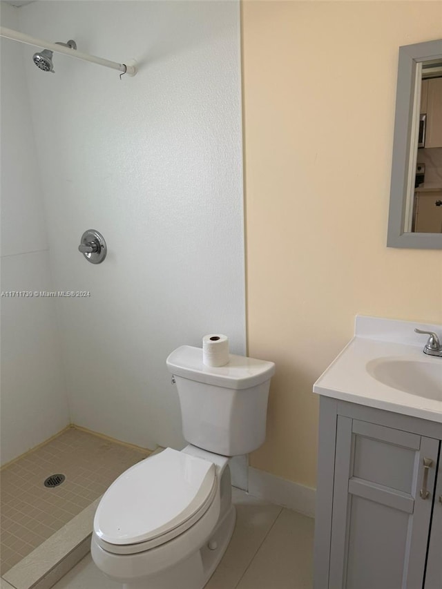 bathroom with tile patterned floors, vanity, toilet, and a shower