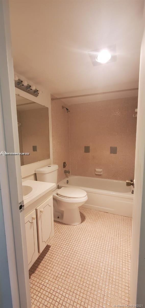 full bathroom featuring tiled shower / bath, vanity, and toilet