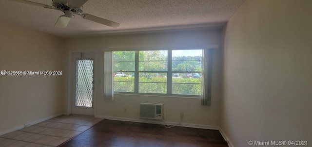 unfurnished room with a textured ceiling, ceiling fan, dark hardwood / wood-style flooring, and a wall mounted air conditioner