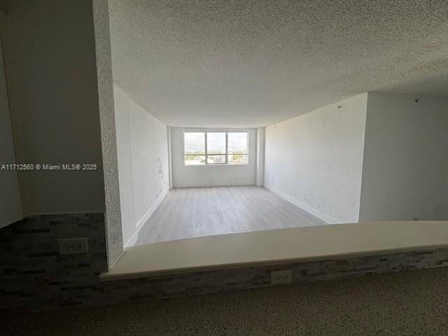 spare room featuring baseboards and a textured ceiling