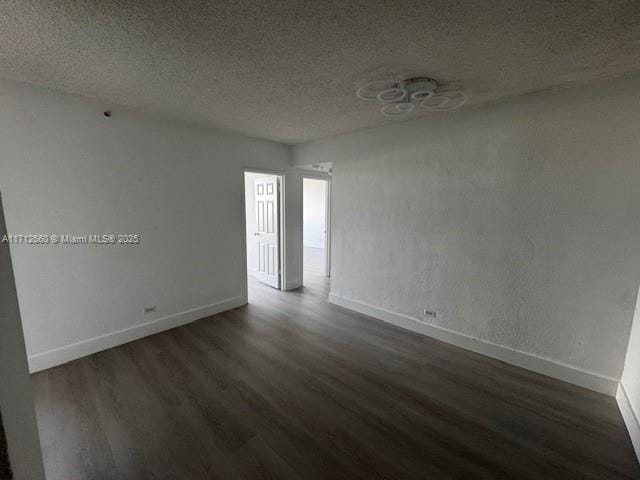 unfurnished room with baseboards, a textured ceiling, and dark wood-type flooring