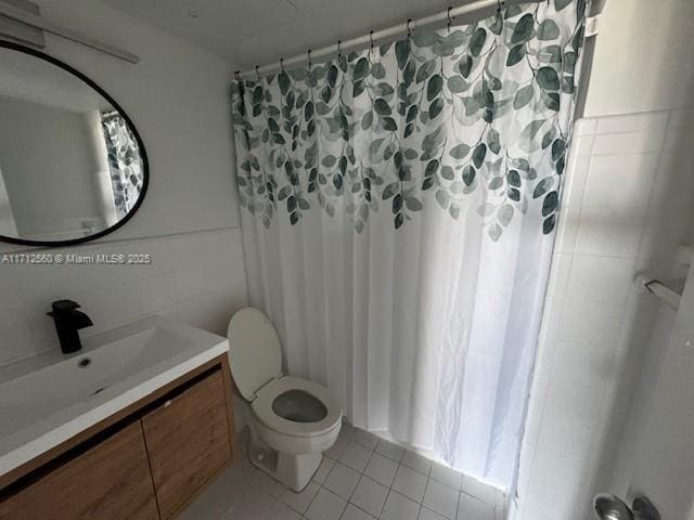 bathroom with tile walls, vanity, curtained shower, tile patterned floors, and toilet