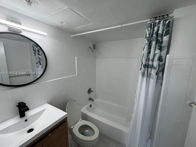 bathroom featuring shower / bath combo with shower curtain, tile walls, toilet, and vanity