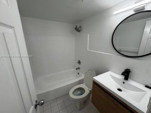 bathroom with tub / shower combination, toilet, tile walls, vanity, and tile patterned flooring