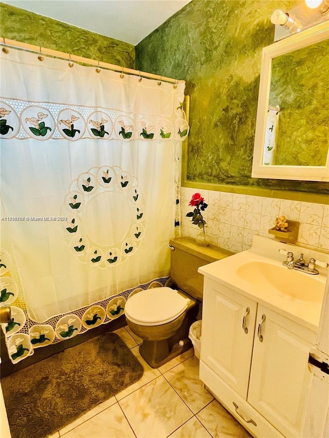 bathroom with vanity, toilet, and tile walls