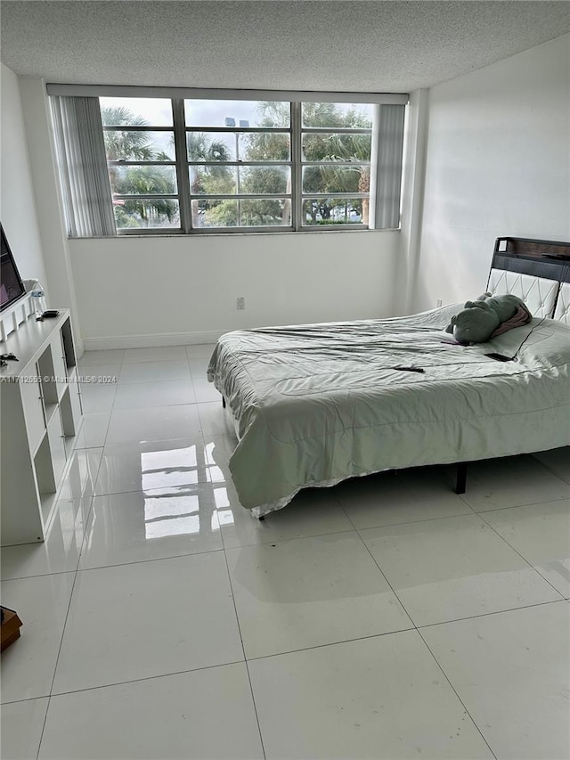 tiled bedroom with a textured ceiling and multiple windows