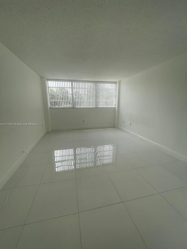 tiled empty room featuring a textured ceiling