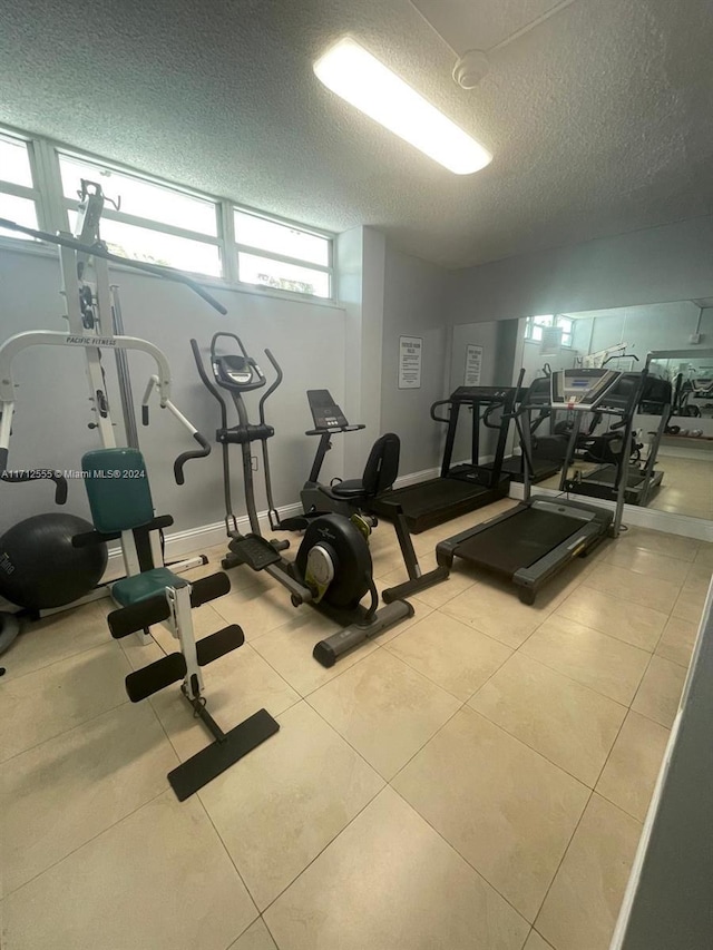 workout area featuring light tile patterned flooring and a textured ceiling