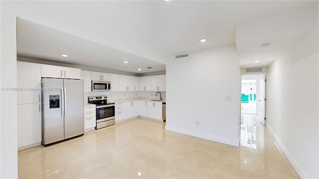 kitchen with light tile patterned floors, stainless steel appliances, white cabinetry, and sink