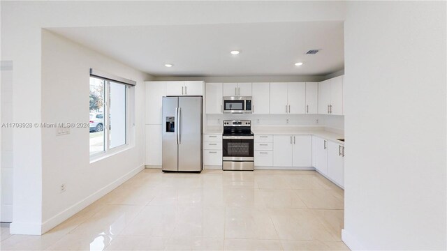 kitchen with white cabinets, appliances with stainless steel finishes, and light tile patterned flooring