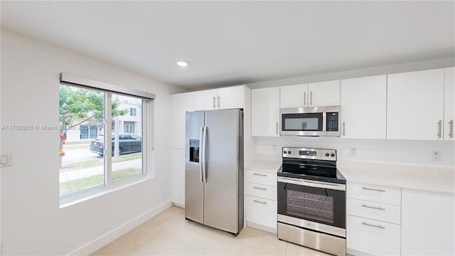 kitchen featuring appliances with stainless steel finishes, light tile patterned floors, and white cabinetry