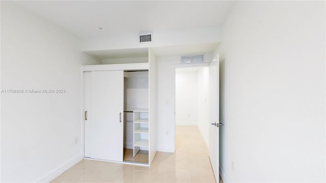 unfurnished bedroom with light tile patterned floors and a closet