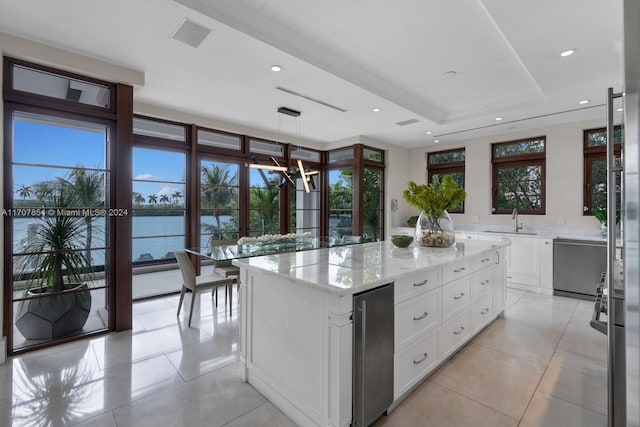 kitchen featuring white cabinetry, a center island, a water view, and a healthy amount of sunlight